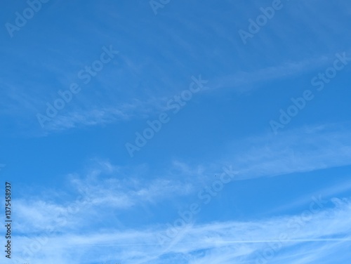 Blue Skies with wispy chemtrail aeroplane lines and fluffy white clouds