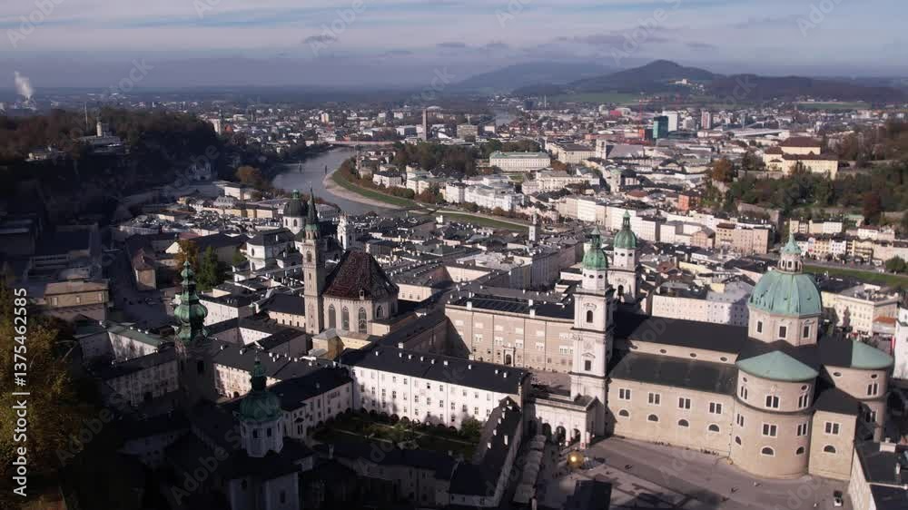 Drone view of Fortress Hohensalzburg with river, greenery and urban buildings under cloudy sky Drone view of Fortress Hohensalzburg with river, greenery and urban buildings under cloudy sky