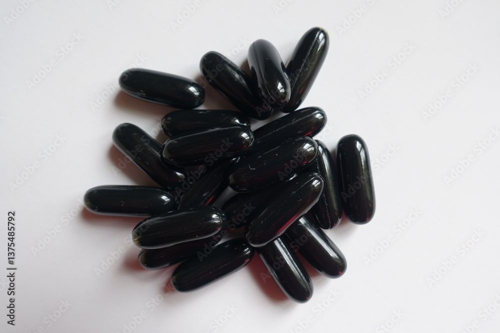 Closeup of heap of black softgel capsules of activated charcoal