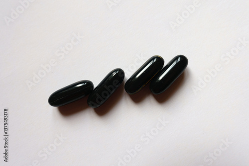 Obraz na płótnie 4 black softgel capsules of activated charcoal from above w salonie