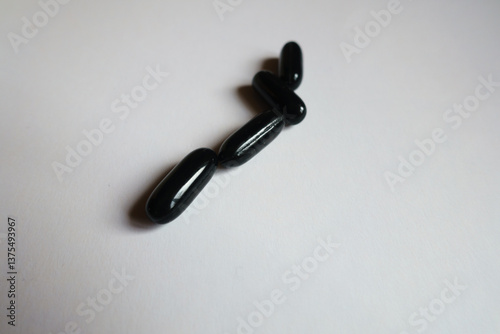 Obraz na płótnie Closeup of four black softgel capsules of activated charcoal w salonie