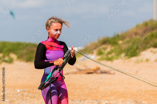 A young female kitesurfer unwinds and straightens the lines of her kite before riding. Preparing the kite for kitesurfing
