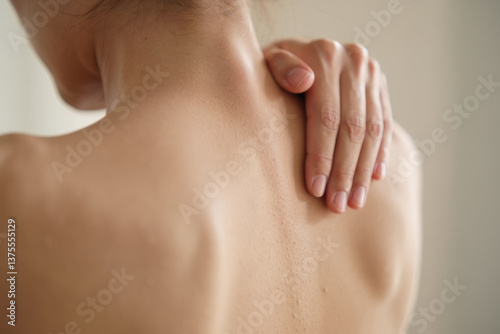 Female adult asian touching sore shoulder with hand