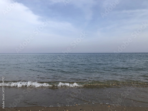 Fototapeta Naklejka Na Ścianę i Meble -  A calm view of the sea to the horizon, a coastal strip, whitecaps on the sea, background, texture