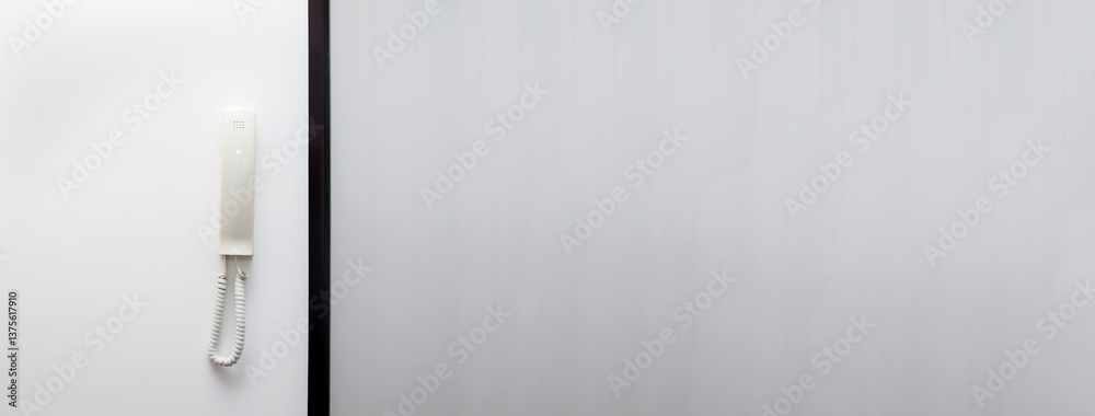 A modern intercom system with a white telephone receiver, displayed on a clean, minimal banner with copy space. The sleek design emphasizes modern communication and security systems