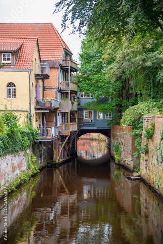 Obraz na płótnie Charming Historic Canal with Buildings and Lush Greenery w salonie