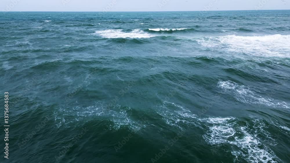 Aerial view of ocean waves crashing and creating white foam on deep green water Aerial view of ocean waves crashing and creating white foam on deep green water