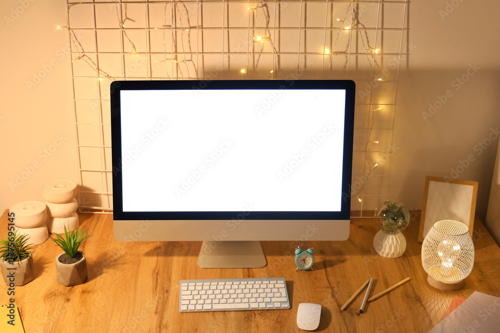 Fototapeta premium Workplace with blank computer monitor, pin board and glowing lights in office at night