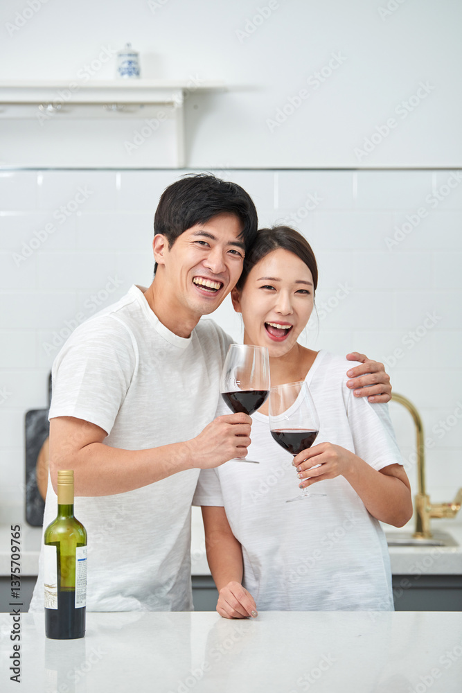 Fototapeta premium A young newlywed couple enjoying wine at the kitchen table on holiday, having a happy time.