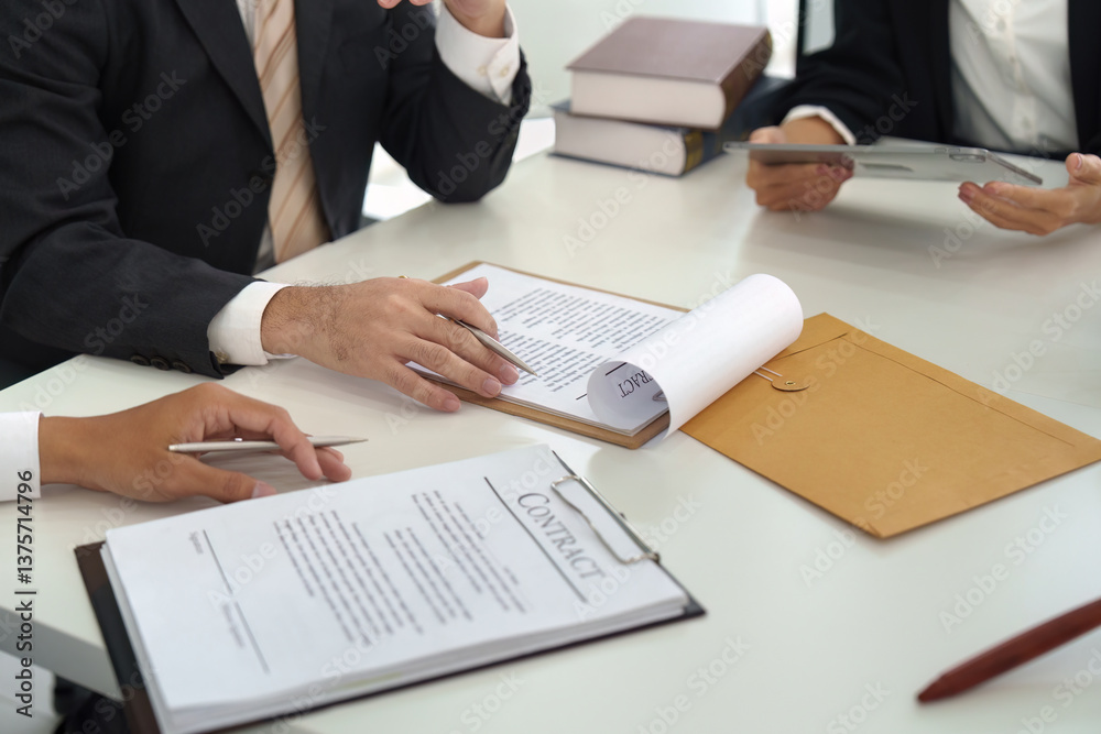 Obraz premium Contract Review and Legal Discussion. Legal professionals analyzing contract details and strategizing during a focused meeting.