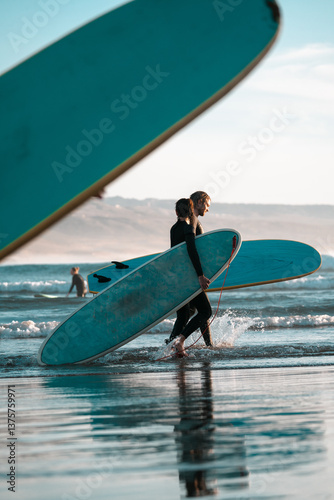 Surfing couple man and woman carrying surfboards