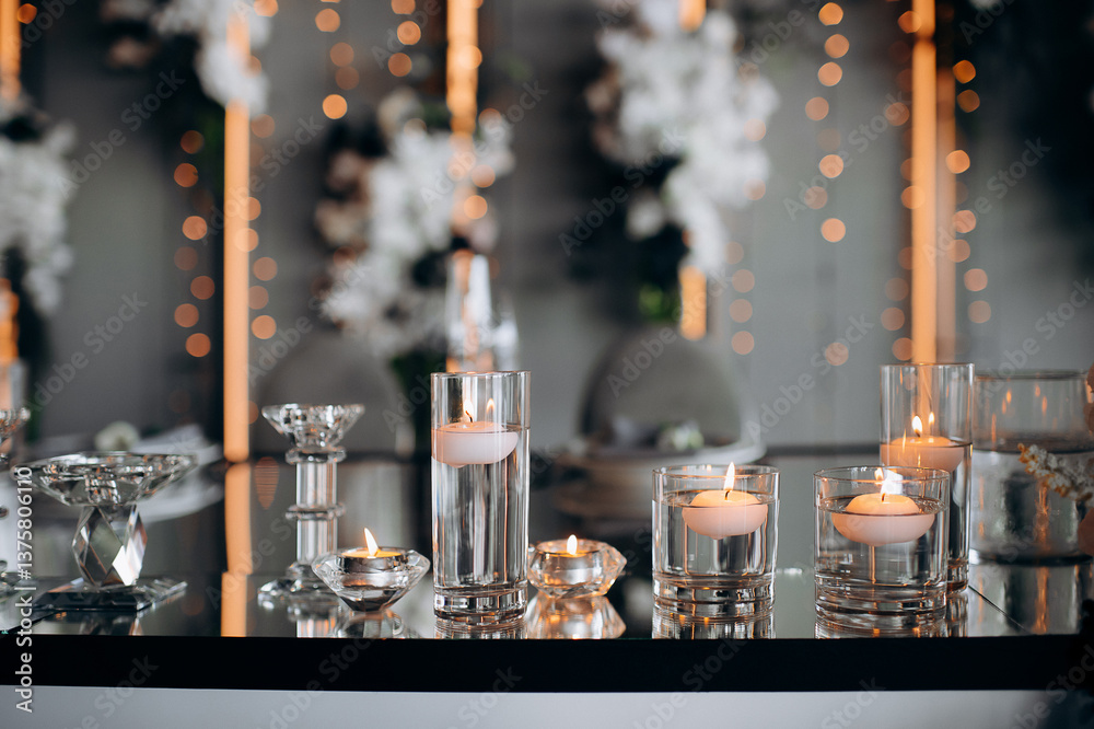 Floating candles in glass globes burning on a mirrored presidium of the newlyweds in a restaurant, creating an elegant and romantic atmosphere for the celebration