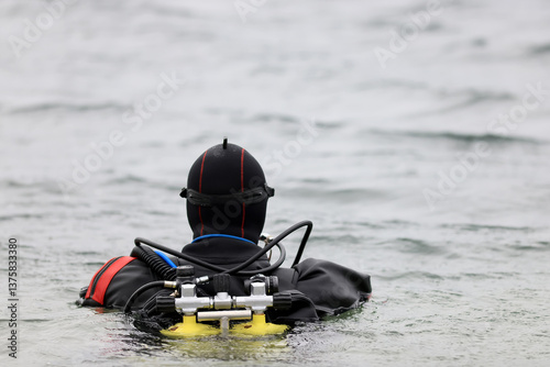 Diver in a dry suit prepares to dive into cold water, extreme diving