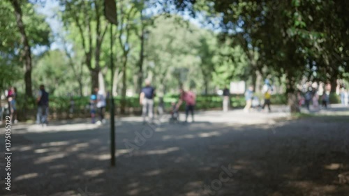 Wallpaper Mural Blurry people strolling through sunlit villa borghese gardens with lush greenery under a clear sky, capturing an outdoor vibrant summer day in rome. Torontodigital.ca