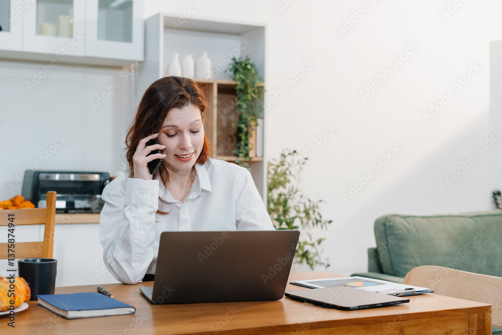 Lifestyle people, using laptop computer and smartphone sitting in the kitchen. Happy mature female, entrepreneur, small business owner working online at home office. Lifestyle people, using laptop computer and smartphone sitting in the kitchen. Happy mature female, entrepreneur, small business owner working online at home office.