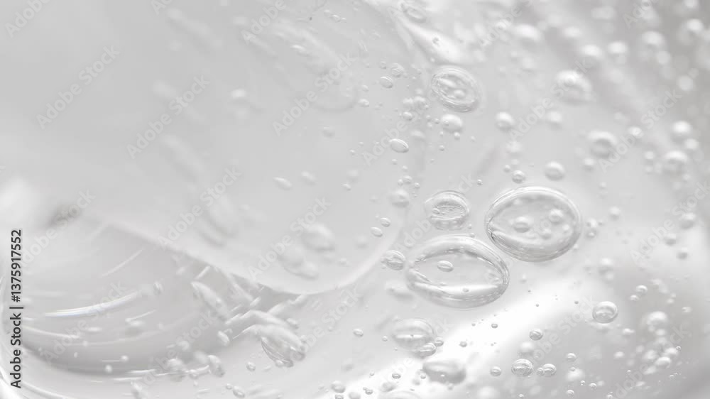 Transparent gel texture with bubbles is mixed with a cosmetic spatula, macro.
