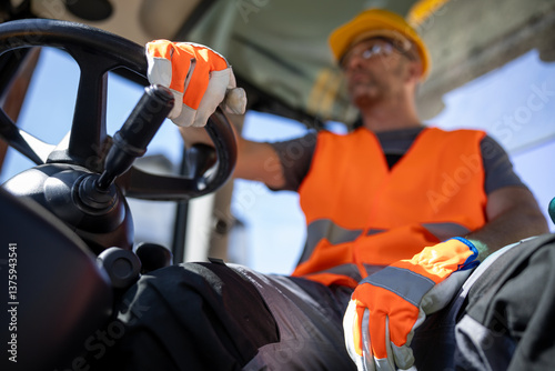 Construction worker driving heavy machinery during daytime work shift in an urban setting