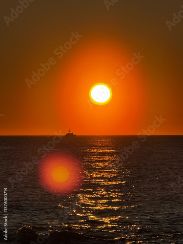 Obraz na płótnie Sunset over ocean with boat and golden sun reflection w salonie