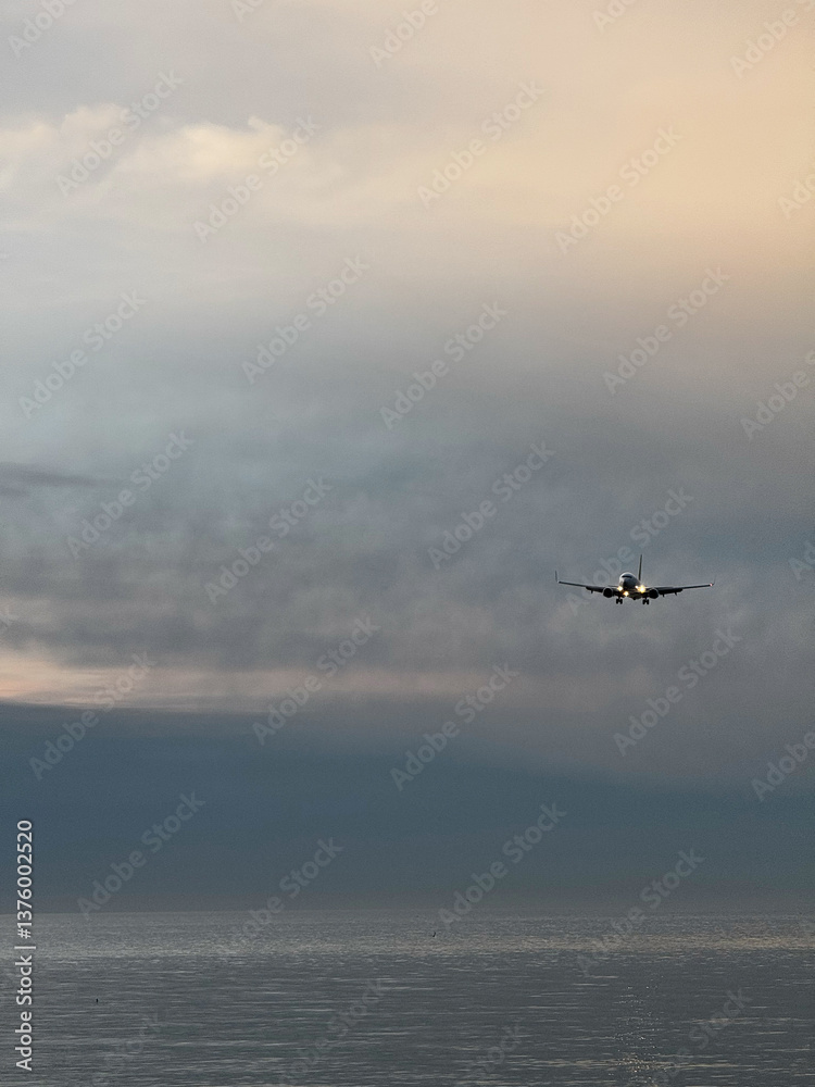 Airplane Approaching Over Calm Ocean at Dusk