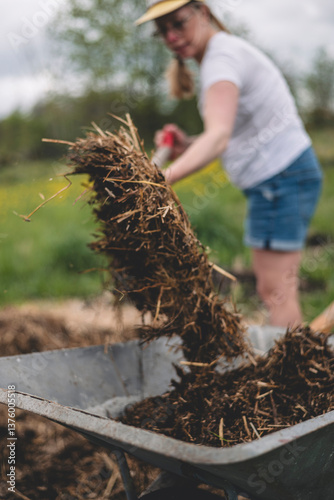 Wet compost in wheelbarrow with woman in background photo