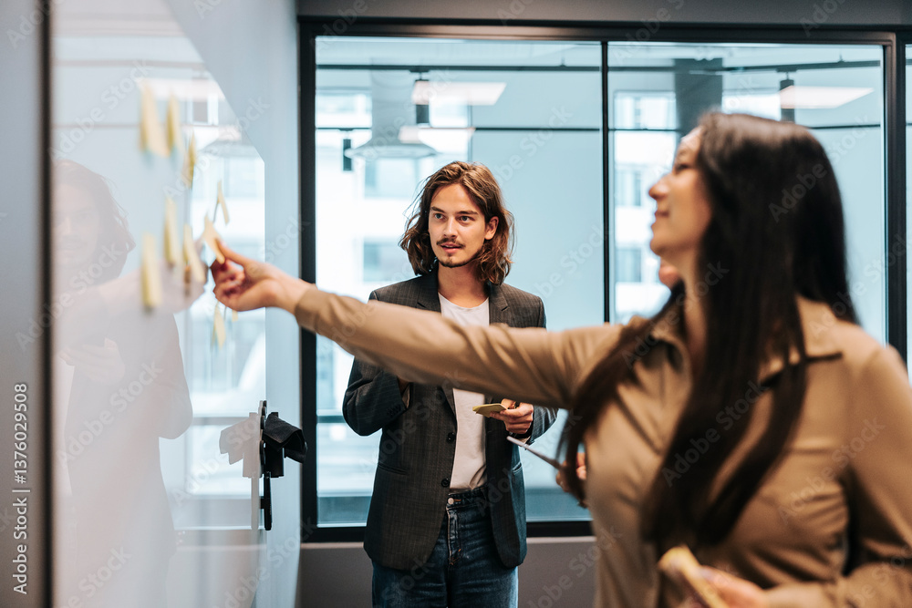 custom made wallpaper toronto digitalBusinesswoman with long hair looking at colleague sticking adhesive note on whiteboard in office meeting room