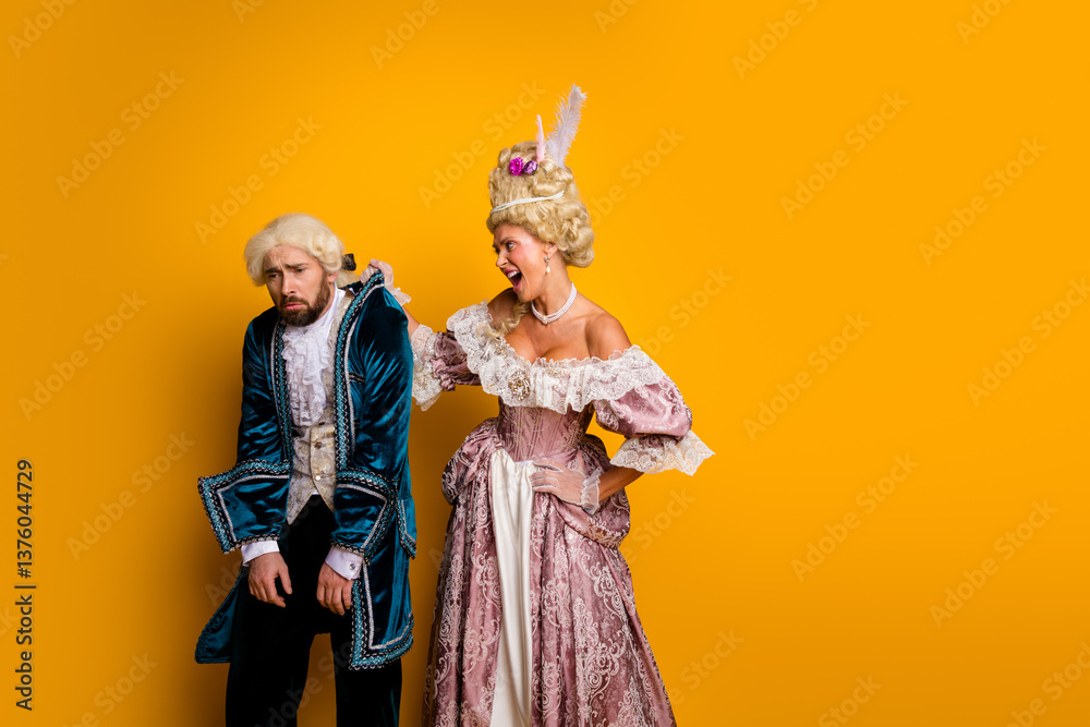 Fototapeta premium Young couple in glamorous vintage costumes posing against a vibrant yellow backdrop