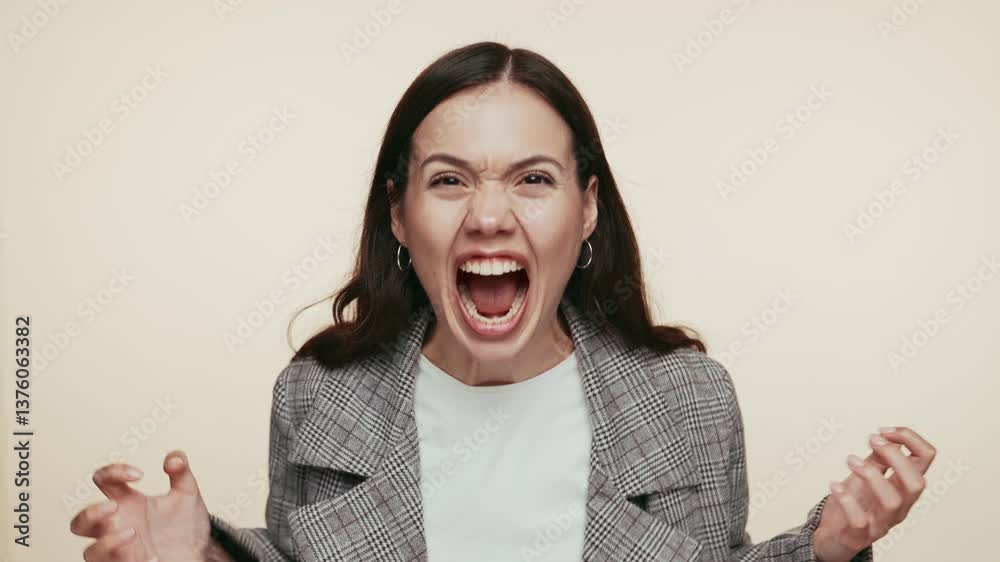 Young woman in a blazer, her face full of anger and fury as she screams loudly against a plain background. Young woman in a blazer, her face full of anger and fury as she screams loudly against a plain background.