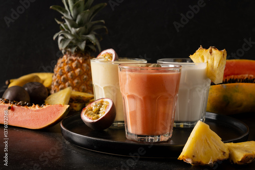 Tropical Pineapple and Papaya lassie, cocktail or smoothie on black background. Traditional healthy vegan Asian beverage. Close up.
