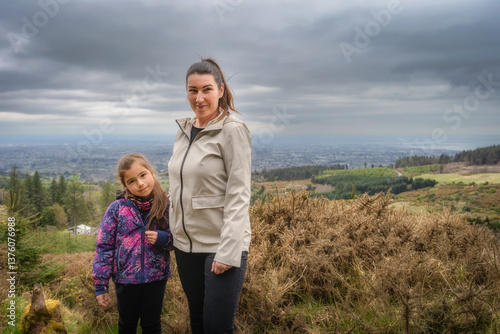 Obraz na płótnie A mother and daughter happily pose together on a picturesque hillside, surrounded by a stunning and colorful scenic view in the background, creating a memorable moment, Wicklow, Dublin, Ireland w salonie