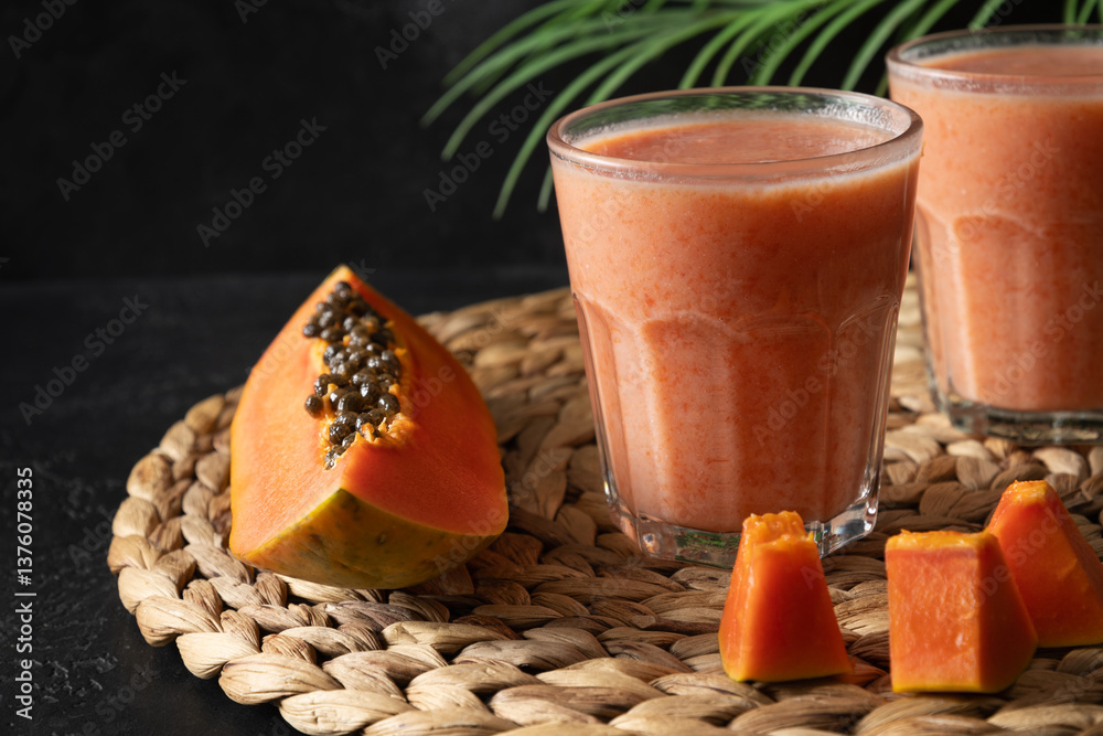 Asian traditional Papaya lassi, smoothie, tropical cocktails or juice on black background. Freshness summer beverage of water, fruits and ice. Close up. Copy space.