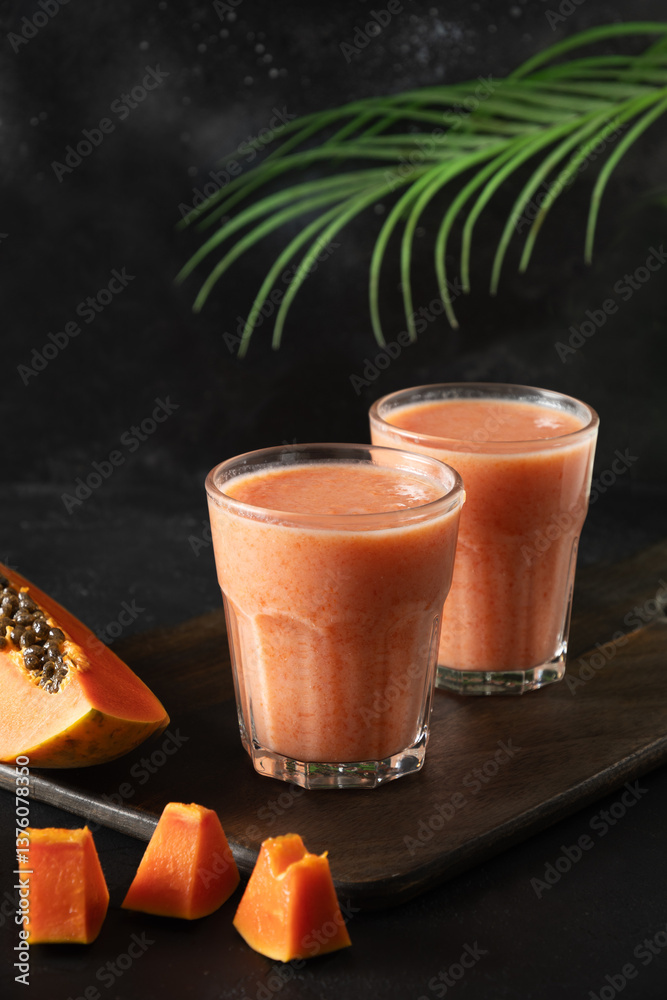 Asian two Papaya lassi, smoothie or tropical cocktails on black background. Summer beverage of water, fruits and ice. Vertical. Close up.