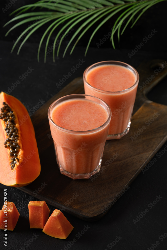 Asian two Papaya lassi, smoothie or tropical cocktails on black background. Summer refreshing beverage of water, fruits and ice. Copy space.