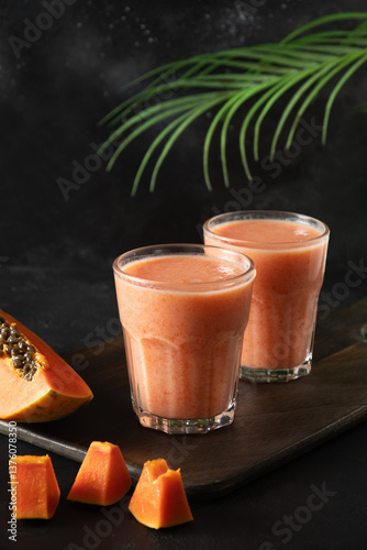 Asian two Papaya lassi, smoothie or tropical cocktails on black background. Summer beverage of water, fruits and ice. Vertical. Close up.