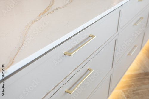 Gold handles on light grey drawers with a white marbled counter top. Kitchen remodel. Kitchen cabinetry.