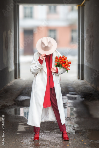 Young beautiful girl in early spring with tulips on the city street.