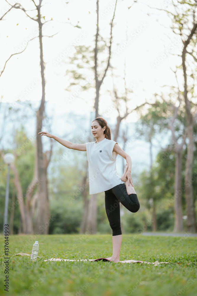 Young Asian woman practicing yoga in a quiet park, gracefully in a relaxed pose, relaxing and strengthening her body, flexibility and relaxation amidst the green grass. Young Asian woman practicing yoga in a quiet park, gracefully in a relaxed pose, relaxing and strengthening her body, flexibility and relaxation amidst the green grass.