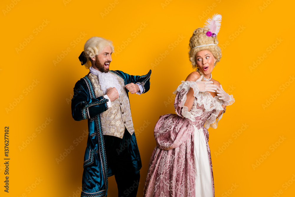 Fototapeta premium Elegant couple wearing royal-themed costumes laughing against orange background