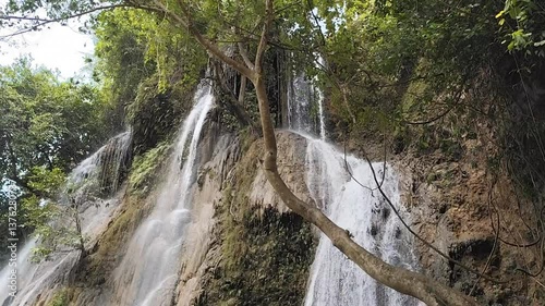 Captivating waterfall cascading down mossy rocks surrounded by lush green foliage footage