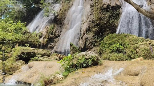 Majestic waterfall cascades down rugged cliffside amidst lush green vegetation