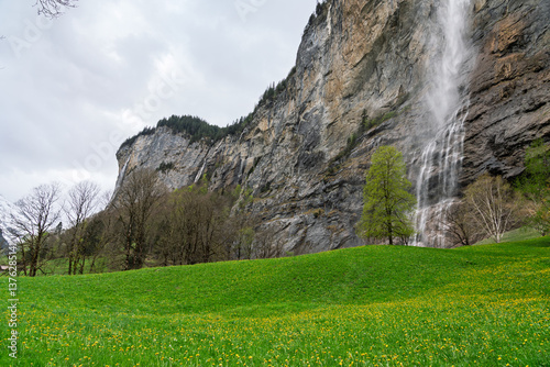 Landscape photo of the Staubbach Falls, sky, lawn and trees.