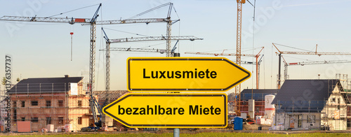 Obraz na płótnie Ein Wegweiser ist beschriftet mit bezahlbare Miete und Luxusmiete vor einem Neubaugebiet für Wohnhäuser - FOTOMONTAGE w salonie