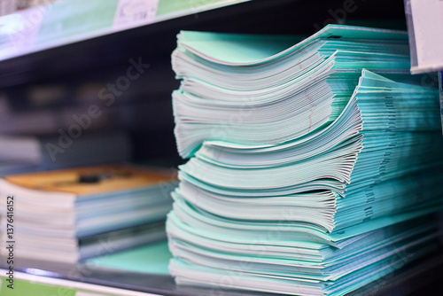Examination papers stacked neatly in a classroom environment, ready for assessment. The green covers indicate they are standardized test materials, organized for student distribution.