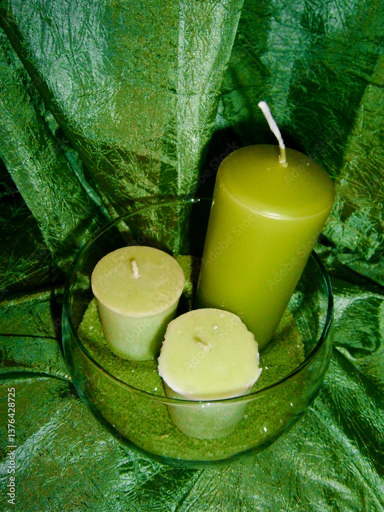 Drei grüne Kerzen im Glas vor einem smaragdgrünen Vorhang