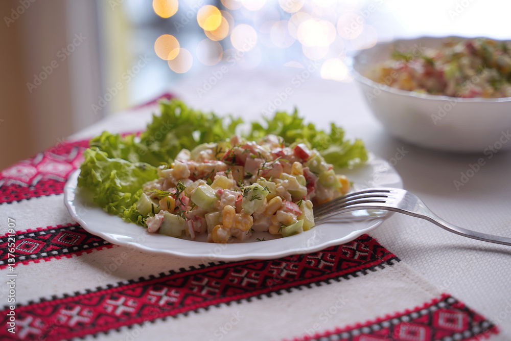 Homemade crab stick salad typical of modern Ukrainian cuisine and other Eastern European cuisines Traditional Ukrainian food on the table with embroidered tablecloth.