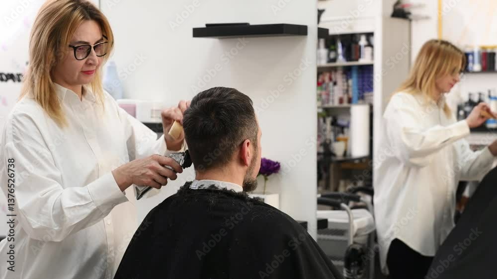 Female barber trims with razor and clipper to male client in beauty salon. Professional barber. Professional hairstylist care Female barber trims with razor and clipper to male client in beauty salon. Professional barber. Professional hairstylist care