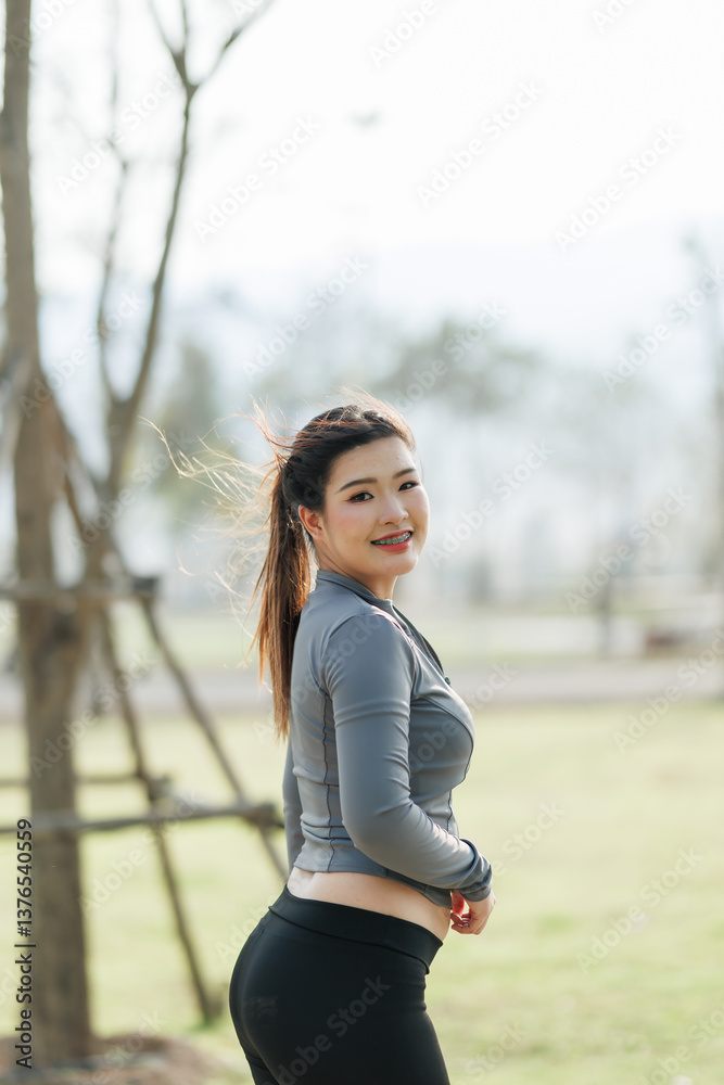 A young woman is jogging in a city park, surrounded by lush trees that provide shade and a refreshing atmosphere. A young woman is jogging in a city park, surrounded by lush trees that provide shade and a refreshing atmosphere.