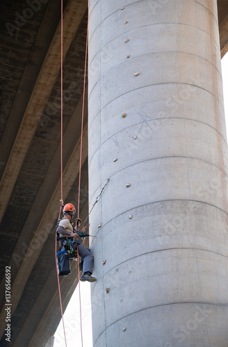 Rope access technician working on bridge pylon inspection and maintenance