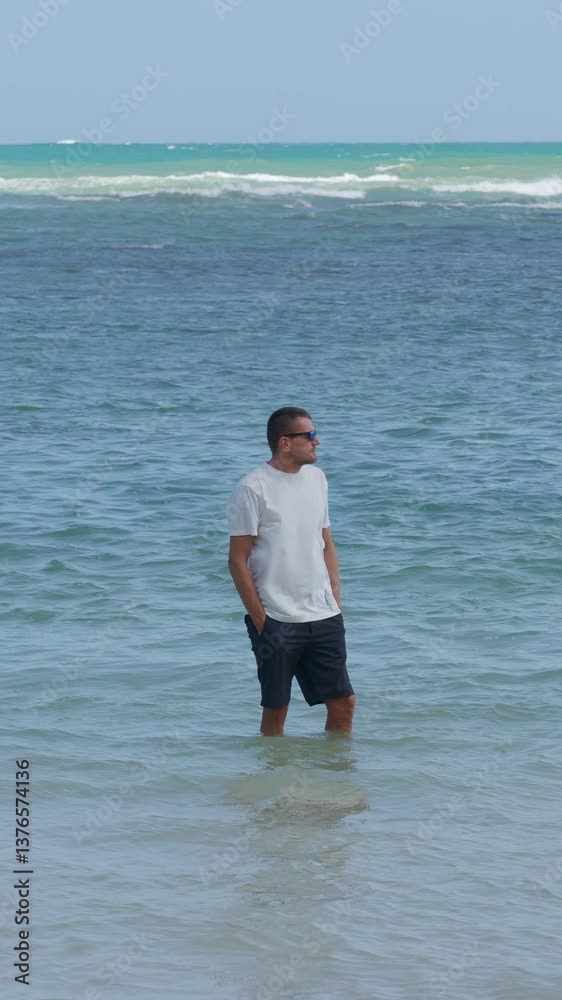 Man wearing sunglasses standing in ocean water at daytime. Vacation, travel. Man wearing sunglasses standing in ocean water at daytime. Vacation, travel.