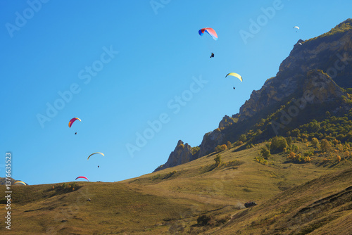 Obraz na płótnie High-altitude paragliding. Many colorful paragliders in the sky on the picturesque background of a rocky mountain. w salonie