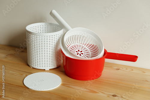 Plastic equipment for making soft cheese and cottage cheese at home. A white uniform, a red ladle.